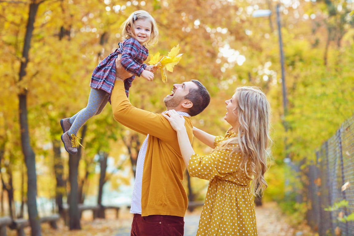 Laughing Parents with Charming Girl in Autumn